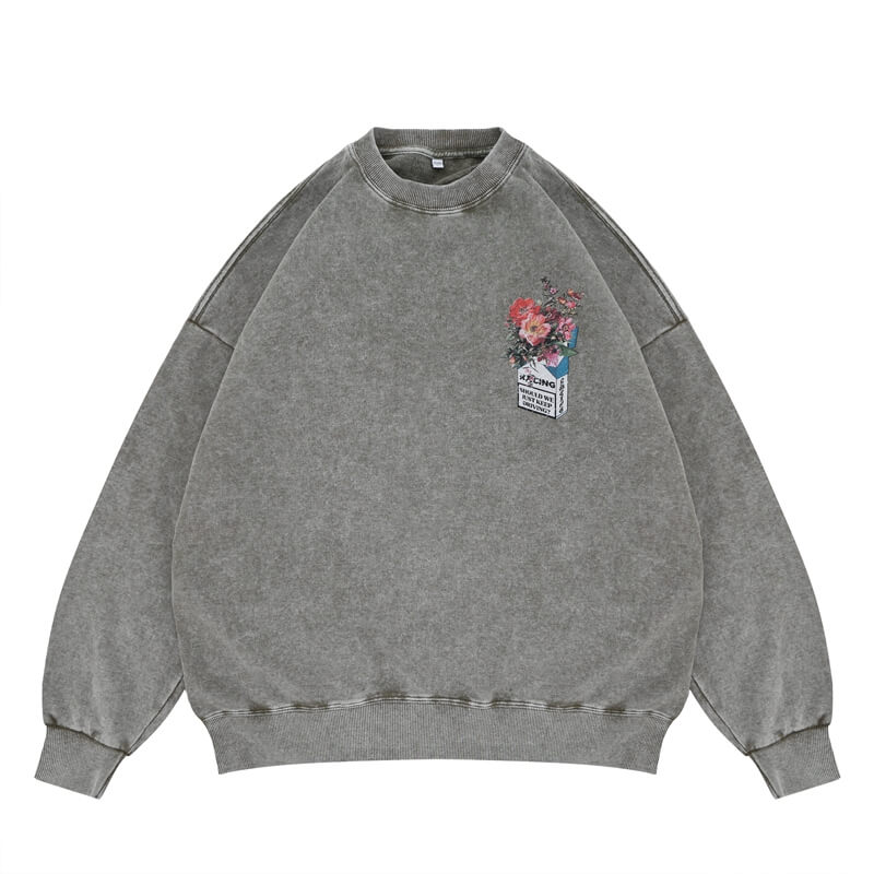 Flat lay of a green vintage wash crew neck sweatshirt with a floral graphic design.